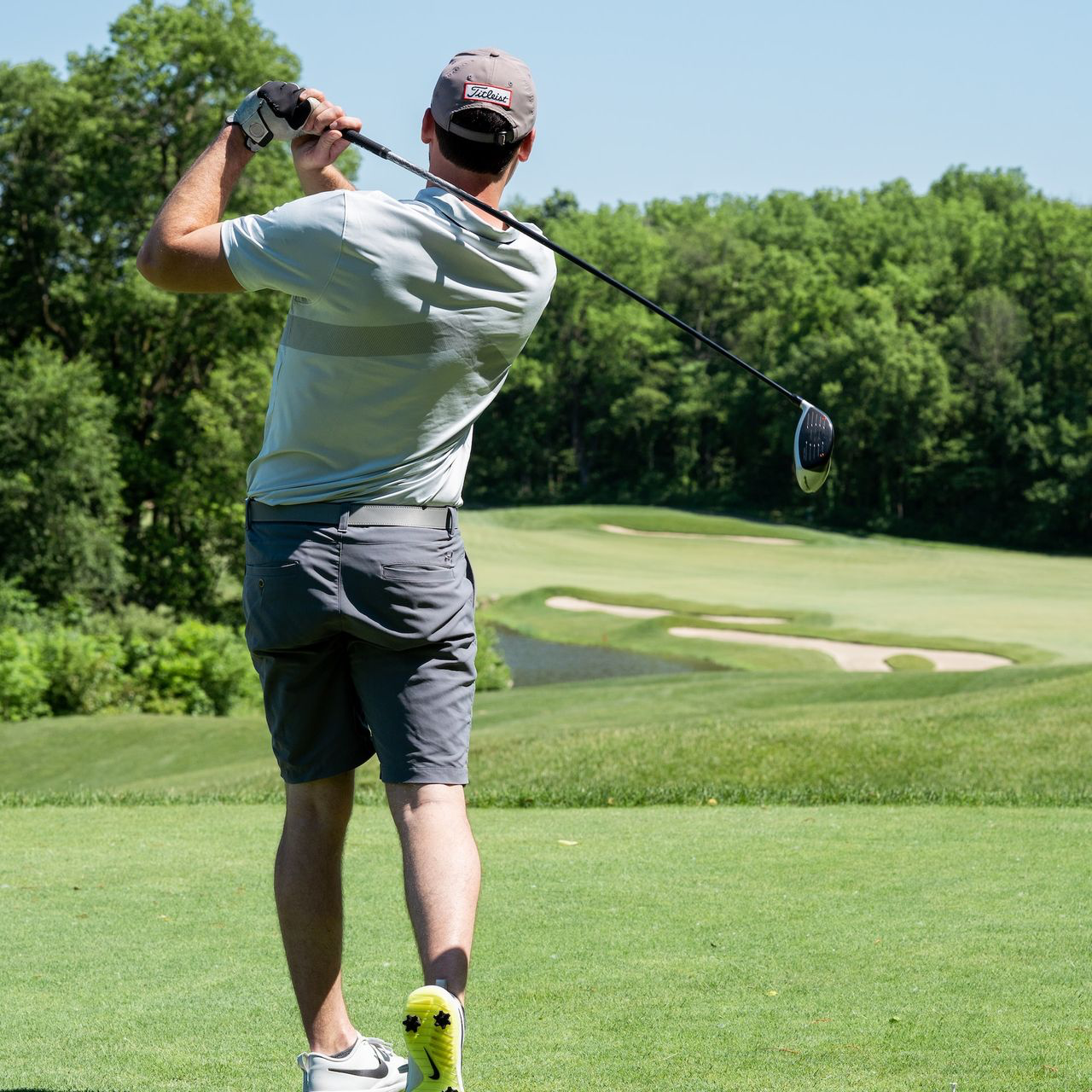 man in white t-shirt and black shorts playing golf during daytime